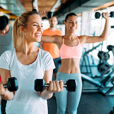 Levantamiento de pesas de dos mujeres en el gimnasio saludables y sonrientes