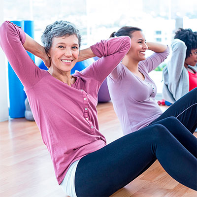 Mujer con camisa rosa haciendo ejercicio durante la menopausia tratamiento menopausia