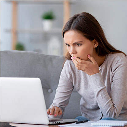 Joven preocupada mirando una laptop, representando los riesgos de las redes sociales y la necesidad de fomentar el amor propio desde la familia.