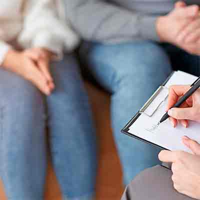 Pareja en sesión de terapia de pareja con un terapeuta tomando notas.