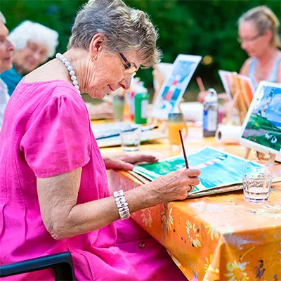 Mujer realizando una actividad de pintura como ejemplo de terapia recreativa en el adulto mayor para mejorar la salud mental.