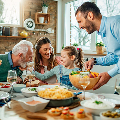 Familia de varias generaciones compartiendo una comida balanceada como parte de hábitos saludables en cada etapa de la vida.