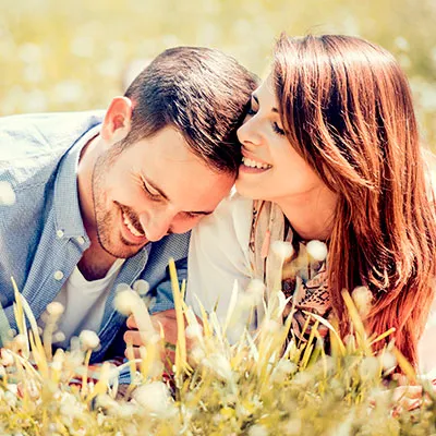 Pareja feliz sonriendo con las cabezas juntas al aire libre, representando los efectos positivos de la química del amor y la liberación de oxitocina y dopamina en el cerebro.