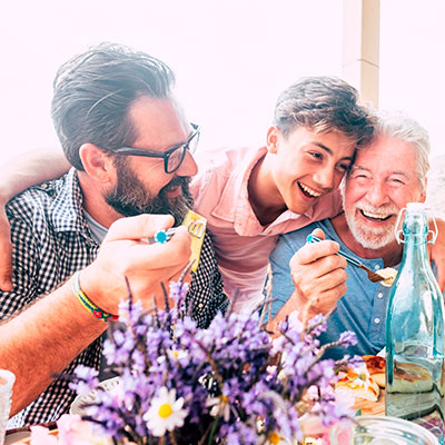 Tres generaciones de hombres celebrando el Dia del Padre en una comida familiar en el campo.