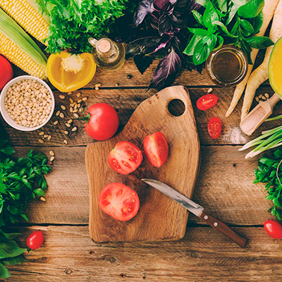 Vegetales de diferente color en una mesa de madera listos para ser picados con un cuchillo