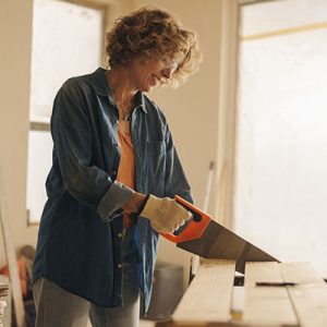 mujer usa una sierra para cortar madera