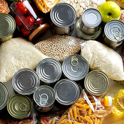 Vista superior de una colección variada de alimentos naturales, alimentos no perecederos, incluyendo alimentos enlatados, bolsas de arroz, pasta y granos, organizados como para una despensa.