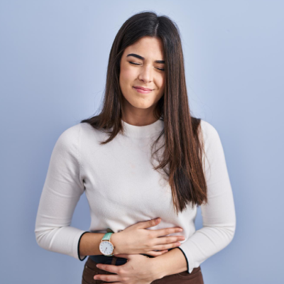 Mujer con expresión de malestar estomacal que resalta la importancia del cuidado del sistema digestivo.