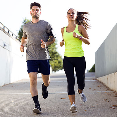 Mujer corriendo junto a un hombre gozando de los beneficios del running