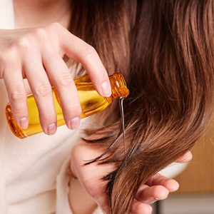 mujer aplicando aceite-para el cabello