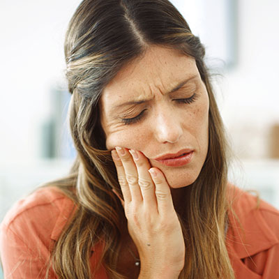 Mujer con dolor agudo por hipersensibilidad dental al contacto con frío o calor
