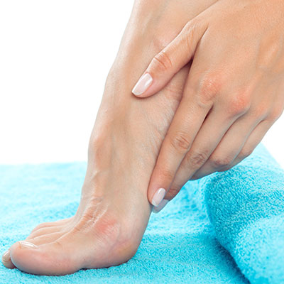 Persona secando sus pies con una toalla limpia para prevenir la aparición de hongos en las uñas y mantener una higiene adecuada.
