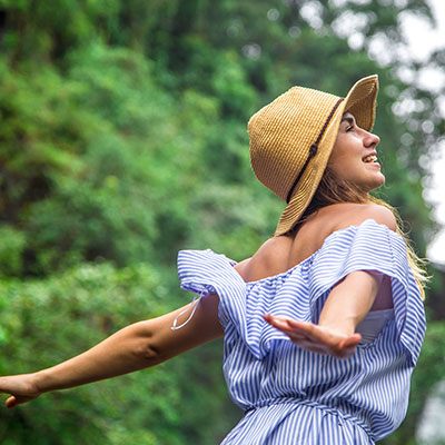 Mujer con sombrero disfrutando de la naturaleza como plan de autocuidado femenino para reducir el estrés.