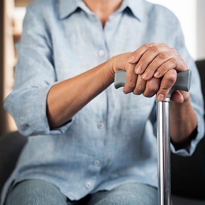 Persona mayor utilizando un bastón de apoyo para evitar caídas en adultos mayores.