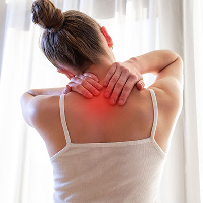 Mujer con dolores musculares comunes en la zona del cuello y hombros por tensión.