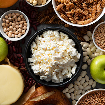 Variedad de alimentos saludables que contienen fibra y explican qué son los prebióticos, incluyendo legumbres, manzanas y granos integrales en cuencos.