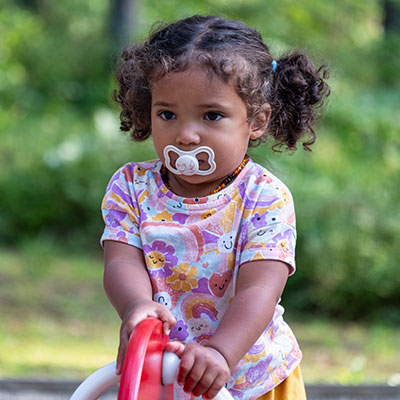 Niña pequeña utilizando un chupete en exteriores, hábito que puede afectar la alineación dental y la salud oral en niños según especialistas.