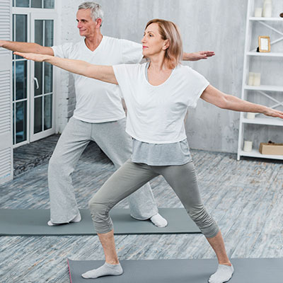 Pareja realizando ejercicios de equilibrio y yoga para evitar caídas en adultos mayores.