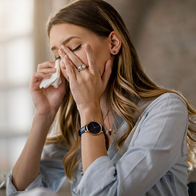 Mujer con dolor de cabeza y presión facial en los senos paranasales debido a síntomas de sinusitis aguda.