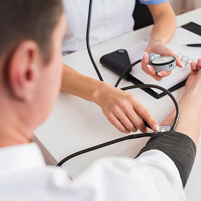 Médico tomando la presión arterial a un paciente con un tensiómetro para prevenir una trombosis cerebral.