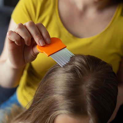 Uso de peineta o liendrera metálica fina en el cabello de un niño para eliminar piojos en niños.