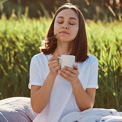 Mujer disfrutando una bebida caliente al aire libre como parte de sus hábitos para manejar los síntomas del síndrome premenstrual.