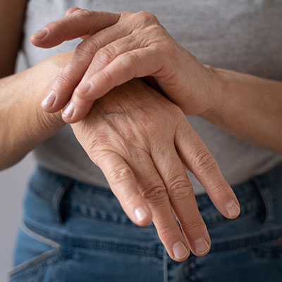Persona mayor sobándose la articulación de la mano por dolor articular leve.